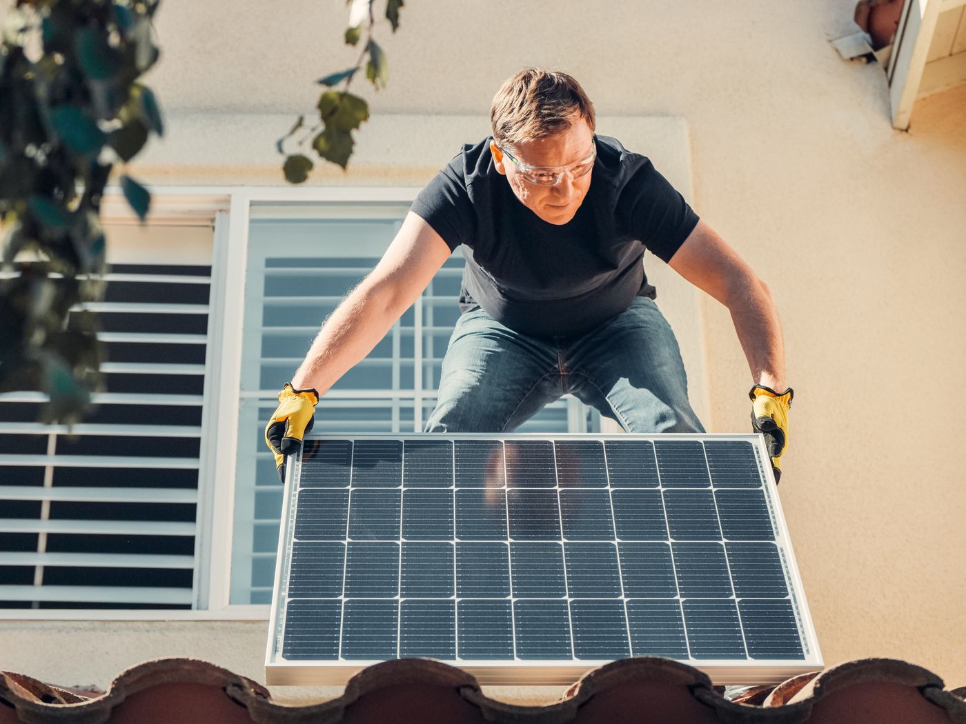 Instalator montujący panel fotowoltaiczny na dachu